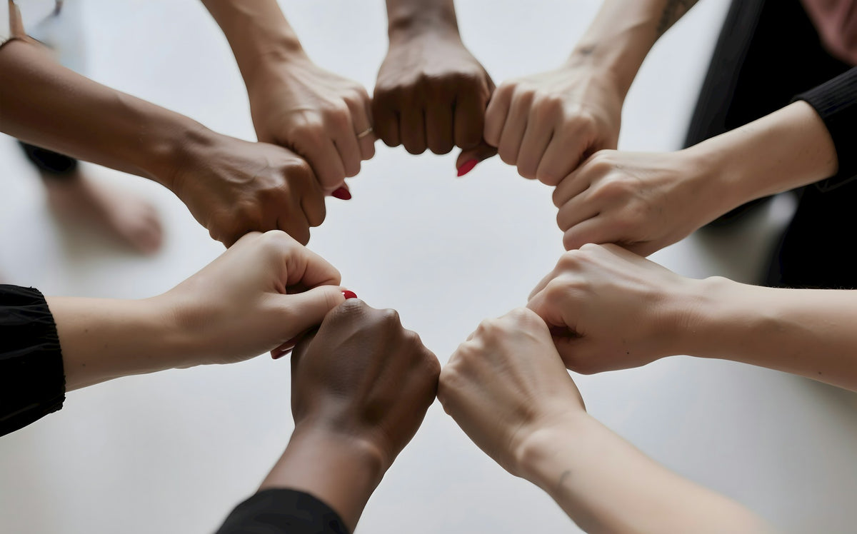 Ein Team bildet einen Kreis aus Fäusten als Zeichen für Zusammenhalt.