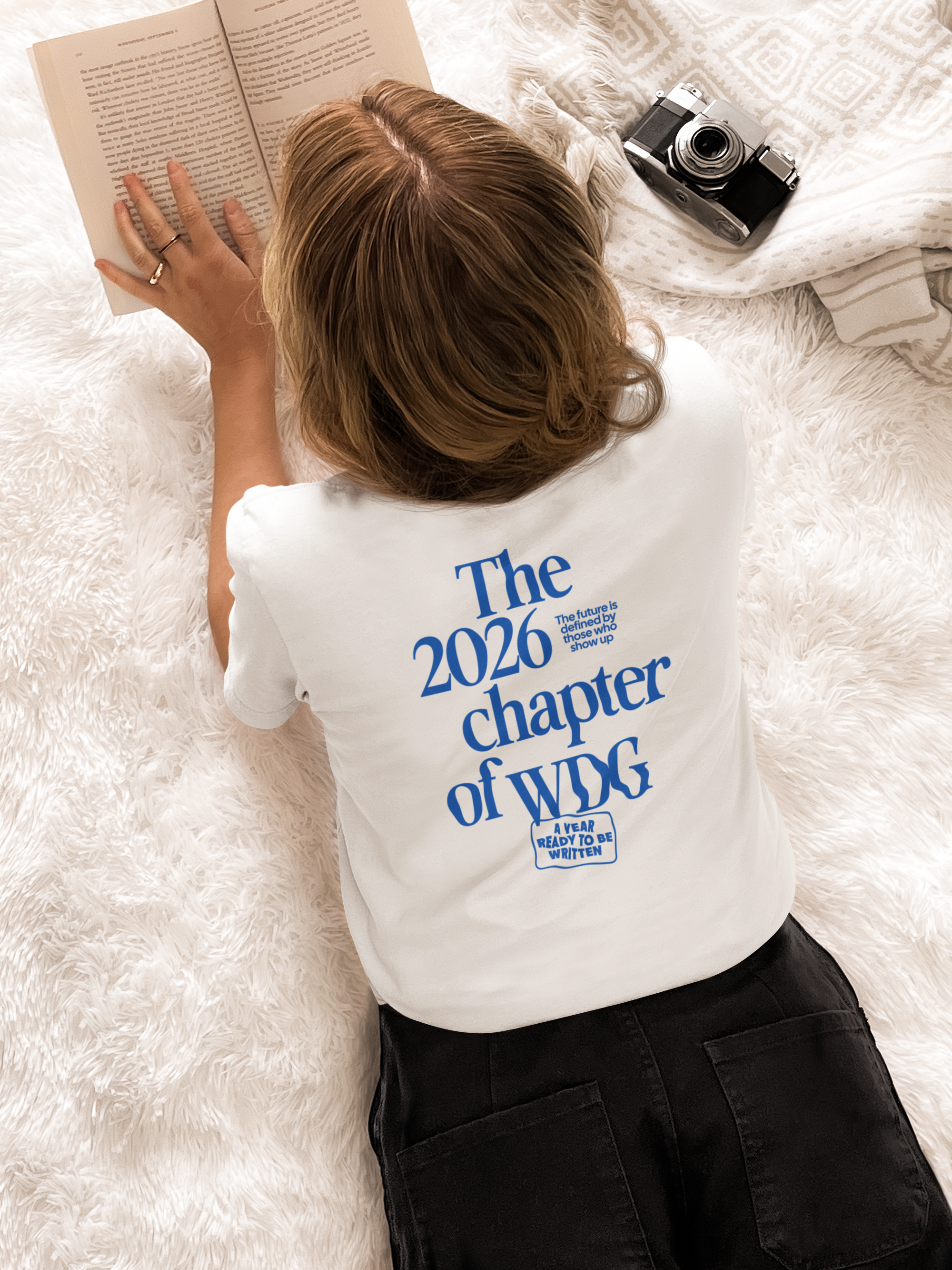 Schülerin liegt auf dem Bauch liest ein Buch und trägt das WDG Chapter 2026 Oversized T-Shirt
